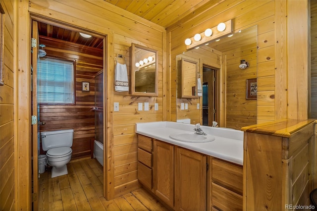 bathroom featuring wooden ceiling, wooden walls, hardwood / wood-style floors, vanity, and toilet