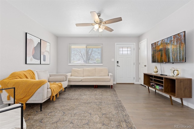 living room with wood finished floors, baseboards, and ceiling fan