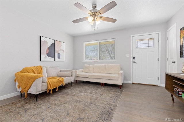 living area featuring ceiling fan, baseboards, and wood finished floors