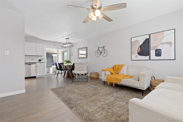 living area featuring baseboards, wood finished floors, and ceiling fan