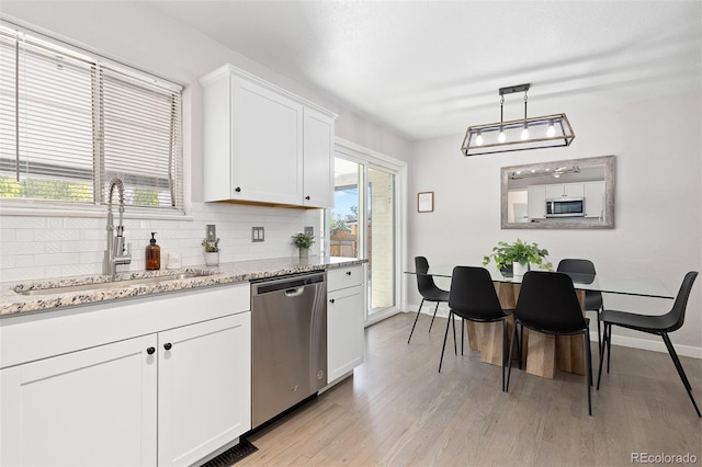 kitchen with a sink, light wood-type flooring, backsplash, baseboards, and appliances with stainless steel finishes