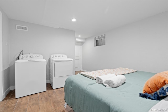 bedroom featuring wood finished floors, washing machine and dryer, baseboards, visible vents, and recessed lighting