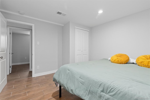 bedroom with wood finished floors, a closet, baseboards, visible vents, and recessed lighting