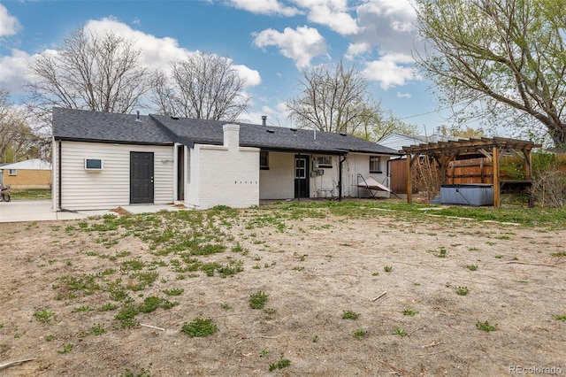 back of property with brick siding, a jacuzzi, a pergola, and a shingled roof