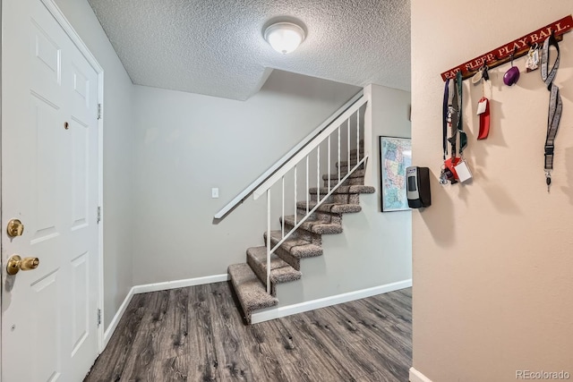 stairway featuring wood-type flooring and a textured ceiling