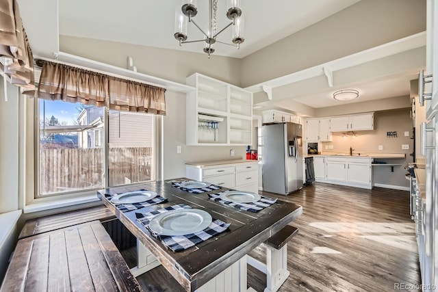 kitchen featuring pendant lighting, white cabinets, appliances with stainless steel finishes, sink, and vaulted ceiling