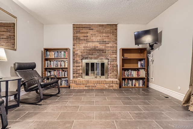 sitting room with a fireplace, a textured ceiling, and tile patterned floors