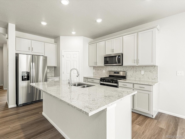 kitchen with stainless steel appliances, a kitchen island with sink, white cabinetry, and sink