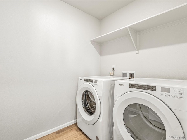 clothes washing area with washer and dryer and light hardwood / wood-style floors