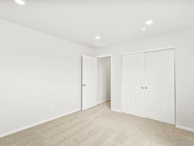 unfurnished bedroom with light carpet and a closet