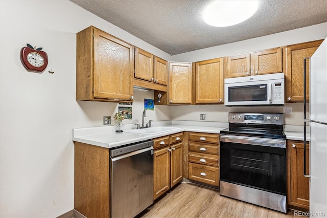 13500 E Cornell Ave Unit 302, Aurora, CO 80014 - kitchen featuring stainless steel appliances, a sink, light wood finished floors, light countertops, and brown cabinetry
