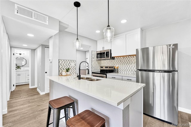 kitchen featuring hanging light fixtures, sink, appliances with stainless steel finishes, tasteful backsplash, and white cabinetry