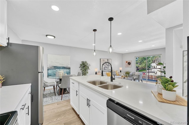 kitchen with sink, stainless steel appliances, light hardwood / wood-style flooring, pendant lighting, and white cabinets