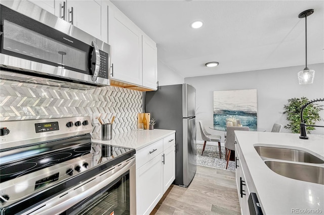 kitchen with pendant lighting, sink, white cabinets, and stainless steel appliances