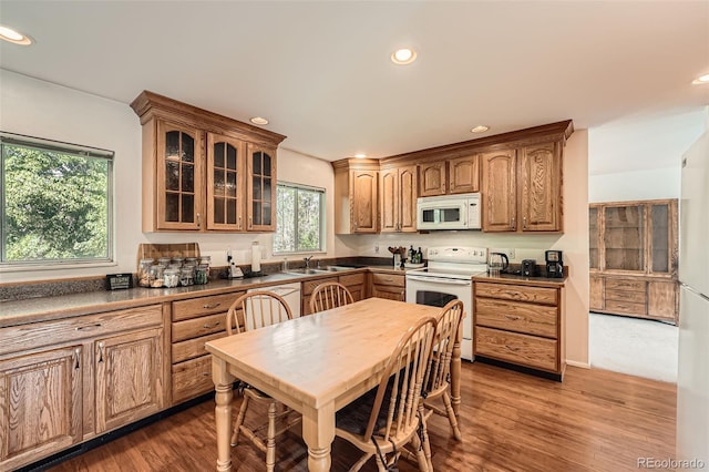 13934 W Warren Dr, Lakewood, CO 80228 - kitchen with white appliances, recessed lighting, glass insert cabinets, wood finished floors, and dark countertops