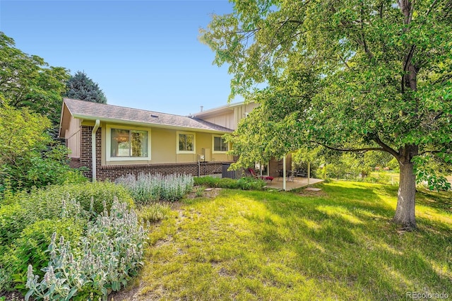 13934 W Warren Dr, Lakewood, CO 80228 - rear view of house with brick siding, a patio, and a yard