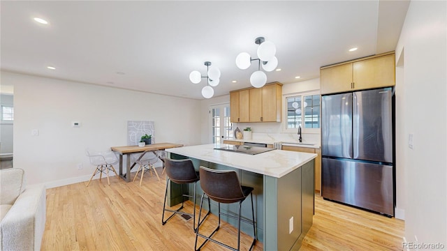 kitchen featuring a kitchen island, light brown cabinetry, stainless steel refrigerator, and light hardwood / wood-style flooring