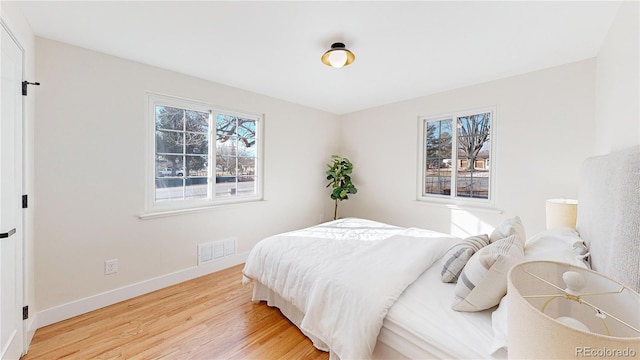 bedroom featuring multiple windows and light hardwood / wood-style flooring