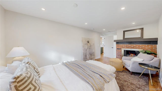 bedroom with hardwood / wood-style floors and a fireplace