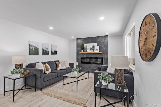 living room with a tile fireplace and light hardwood / wood-style flooring