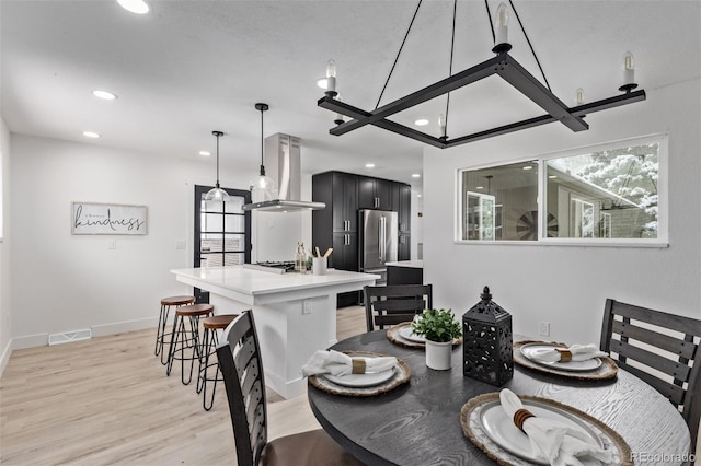 dining area with plenty of natural light, light hardwood / wood-style floors, and an inviting chandelier