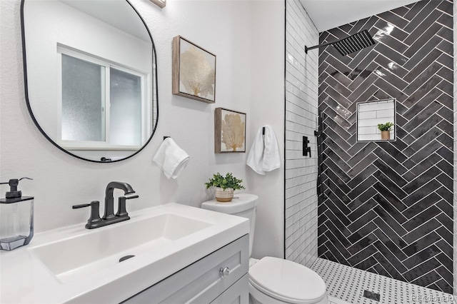 bathroom with a tile shower, vanity, and toilet