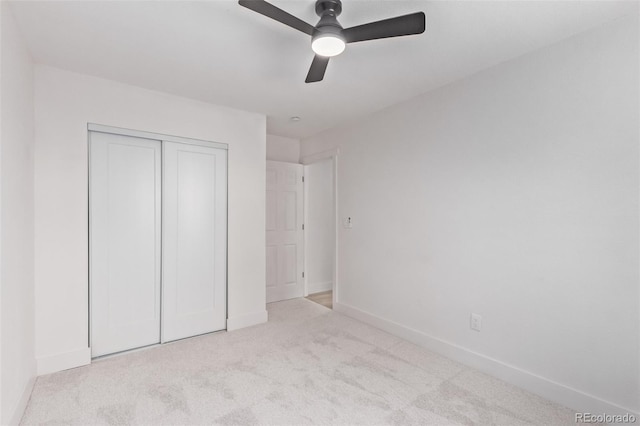 unfurnished bedroom with ceiling fan, a closet, and light colored carpet