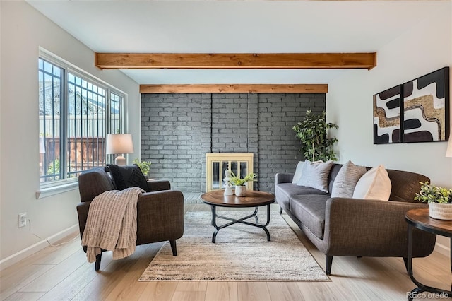 living area featuring baseboards, a brick fireplace, beam ceiling, and wood finished floors