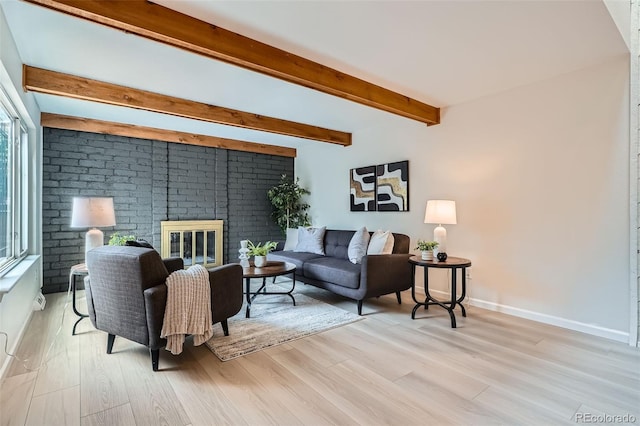 living area featuring a fireplace, baseboards, light wood-style flooring, and beam ceiling