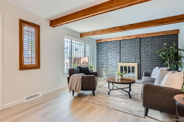 living area with visible vents, baseboards, beam ceiling, and a wealth of natural light