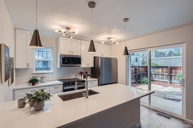kitchen featuring visible vents, plenty of natural light, tasteful backsplash, a sink, and stainless steel appliances
