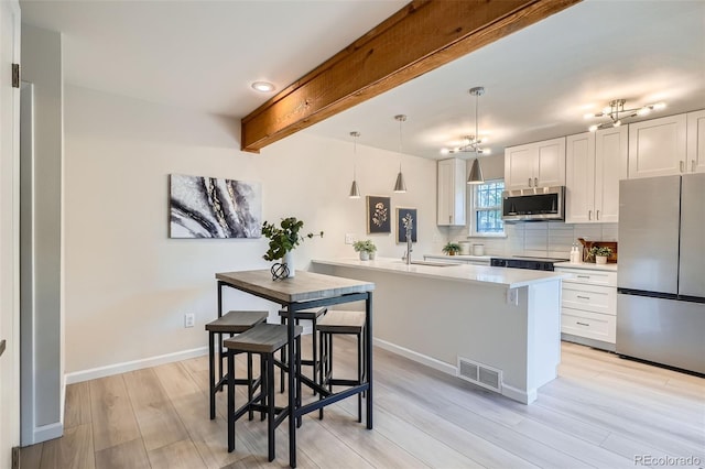 kitchen with visible vents, decorative backsplash, a sink, light wood finished floors, and appliances with stainless steel finishes