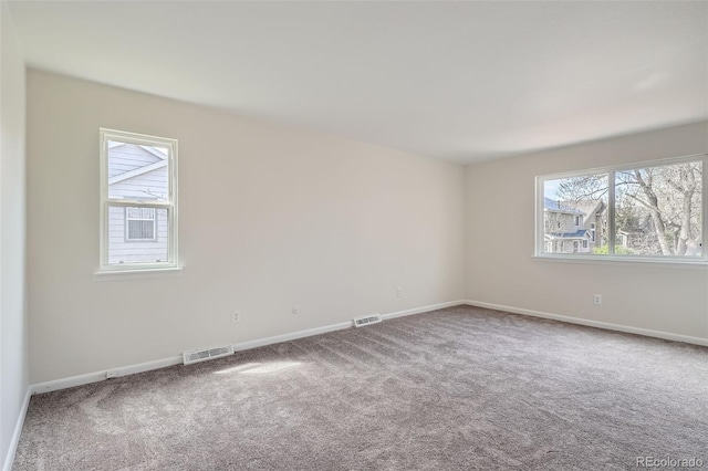 carpeted empty room with baseboards, visible vents, and plenty of natural light