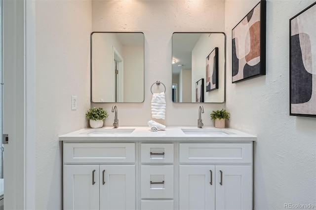 bathroom featuring double vanity, a sink, and a textured wall