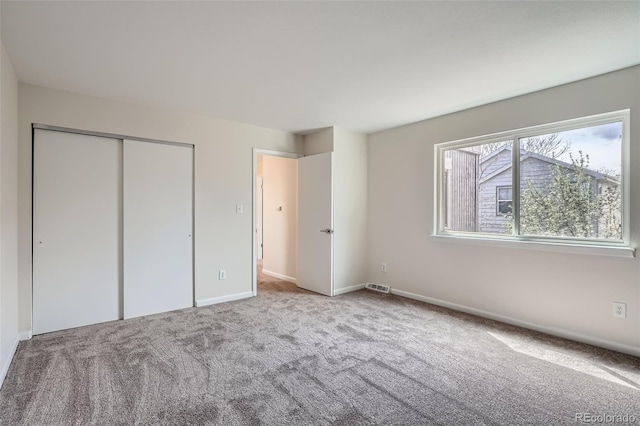 unfurnished bedroom featuring baseboards, carpet, a closet, and visible vents
