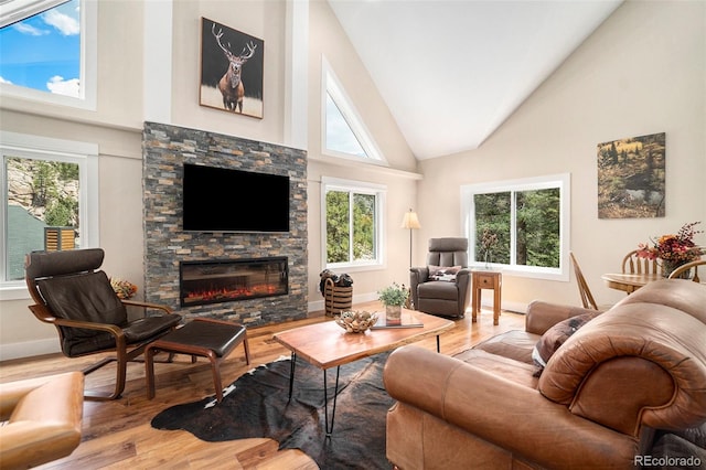 living room featuring hardwood / wood-style floors, a stone fireplace, and high vaulted ceiling