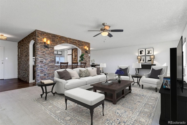 living room with hardwood / wood-style flooring, ceiling fan, and a textured ceiling