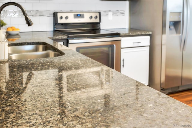 kitchen with sink, dark stone countertops, decorative backsplash, hardwood / wood-style flooring, and stainless steel appliances