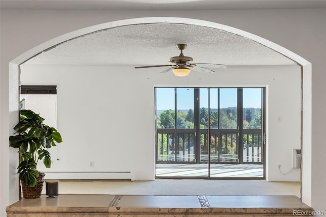 unfurnished living room with ceiling fan, an AC wall unit, a baseboard heating unit, and a textured ceiling