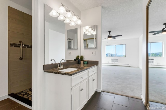 bathroom with vanity, a baseboard heating unit, a wealth of natural light, and a textured ceiling