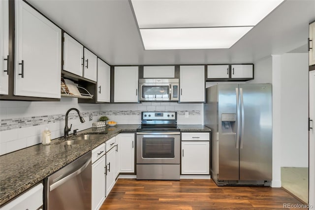 kitchen featuring sink, white cabinetry, dark stone counters, dark hardwood / wood-style flooring, and stainless steel appliances