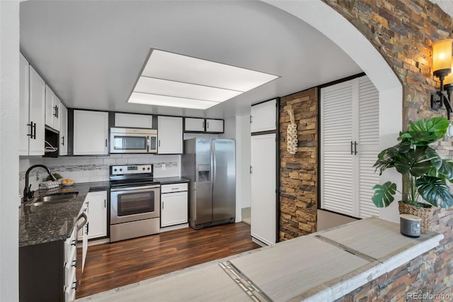 kitchen with tasteful backsplash, appliances with stainless steel finishes, sink, and white cabinets