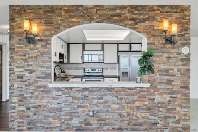 kitchen featuring stainless steel appliances, white cabinetry, sink, and backsplash