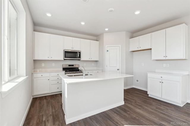 kitchen with white cabinetry, sink, stainless steel appliances, dark hardwood / wood-style flooring, and an island with sink