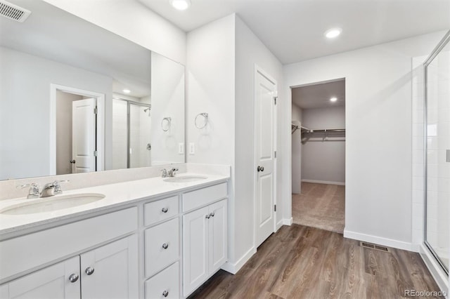 bathroom with hardwood / wood-style floors, vanity, and an enclosed shower