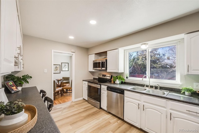 kitchen with white cabinets, light wood-type flooring, stainless steel appliances, and sink