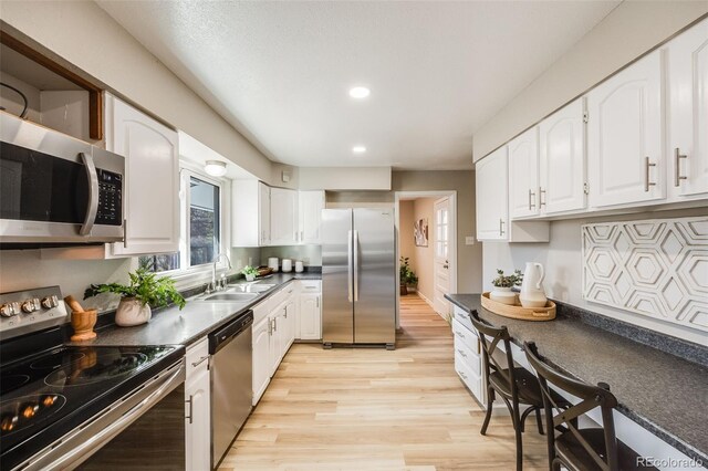 kitchen with white cabinets, light wood-type flooring, stainless steel appliances, and sink