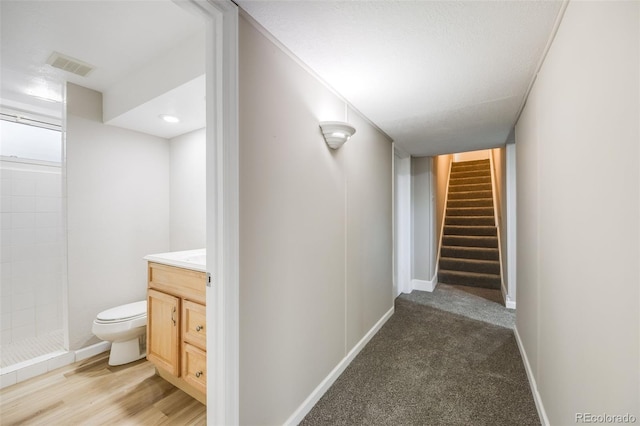 hall with a textured ceiling and light wood-type flooring