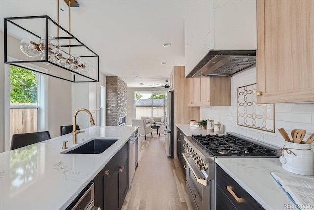 kitchen with pendant lighting, stainless steel appliances, tasteful backsplash, light brown cabinetry, and sink