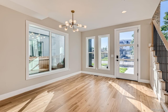 entryway with light hardwood / wood-style floors, a notable chandelier, and a wealth of natural light